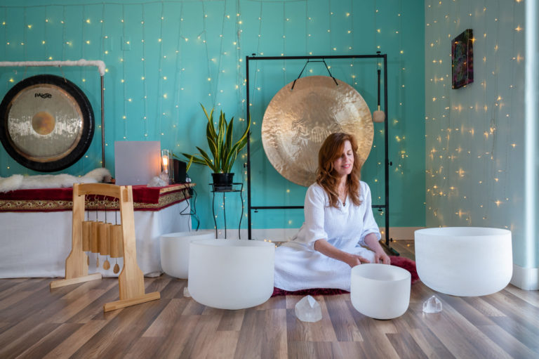 Woman meditating with singing bowls and gongs