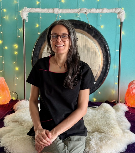 Woman sitting in front of a gong with lights.