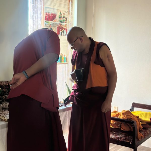 Two monks in traditional robes, indoors.
